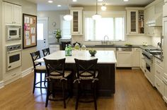 a large kitchen with an island in the middle and chairs at the table, along with white cabinets