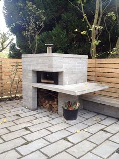 an outdoor fireplace built into the side of a brick wall in a back yard area