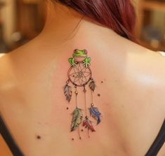 a woman with a tattoo on her back that has a frog sitting on top of it