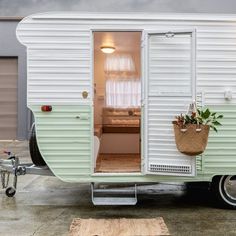 an old camper trailer is converted into a mobile home with plants in the door