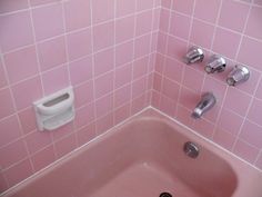 a pink bathtub with two hand soap dispensers on the back wall