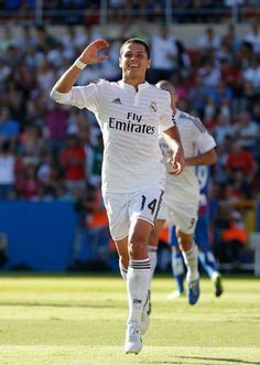 a soccer player is running on the field with his arms in the air as he celebrates