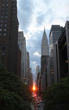 a city street filled with lots of traffic and tall buildings in the background at dusk