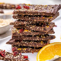 a stack of chocolate orange slices on a plate next to an orange slice and spoon