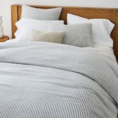 a bed with blue and white striped comforter next to two vases on the nightstand