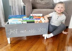 a young boy is sitting on the floor holding a book box with books in it