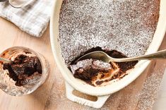 a cake in a pan with a spoon and some powdered sugar on top next to it