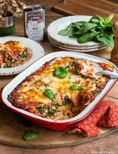 a casserole dish with spinach, cheese and sauce on a wooden table