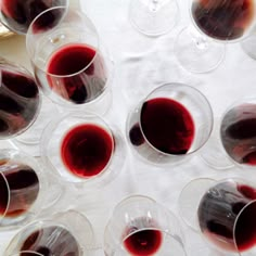 several glasses of red wine sitting on top of a table