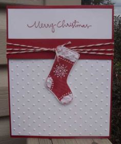 a christmas card with a red stocking hanging from it's side on top of a wooden table