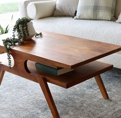 a coffee table with a book on it in front of a white couch and pillows