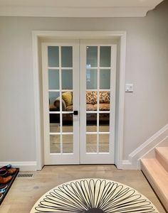 a living room with two doors and a rug on the floor in front of it