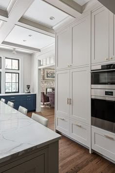 a large kitchen with white cabinets and marble counter tops, along with an island in the middle