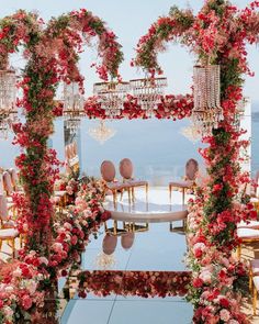 an outdoor ceremony setup with flowers and chandeliers on the water's edge