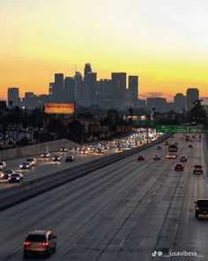 cars are driving on the freeway in front of tall buildings at sunset or dawn with city lights behind them