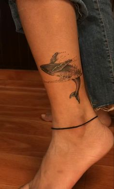 a woman's foot with a tattoo of a dolphin on the side of her leg