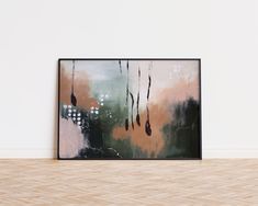 an abstract painting hangs on the wall in front of a wooden floor and white walls