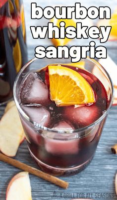 bourbon whiskey sangria in a glass with an orange slice on the rim and cinnamon sticks next to it