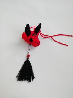 a red stuffed animal with black horns and tassels