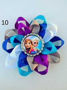 the frozen princess hair clip is attached to a blue, purple and white ribbon flower