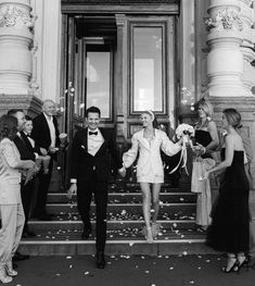 a man in a tuxedo is walking down the steps with his bride and groom