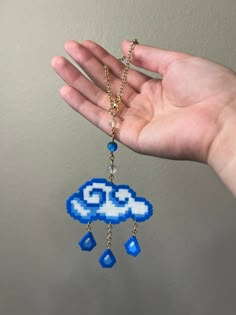 a hand holding a blue and white beaded cloud with raindrops on it