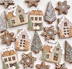 many decorated cookies are arranged in the shape of houses and snowflakes on a white surface