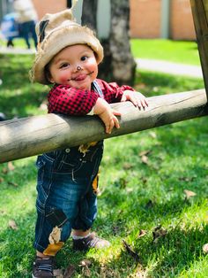 a little boy that is leaning on a wooden fence with his hands on the rail