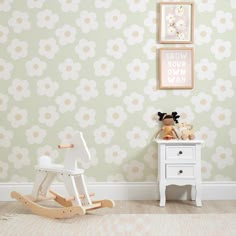 a child's room with green and white wallpaper, a wooden rocking horse and two pictures on the wall