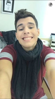 a young man is taking a selfie in the mirror with his cell phone and scarf around his neck