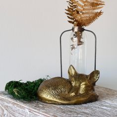 a gold fox statue sitting on top of a wooden table next to a glass bottle