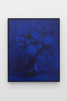 a blue vase with flowers in it on a white wall next to a black frame