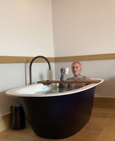 a man sitting in a bathtub holding a cup