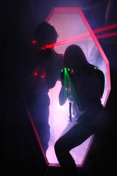 two people standing in front of a mirror with laser lights on their faces and hands