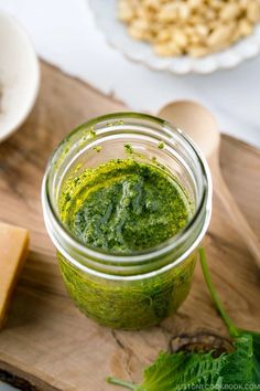 a jar filled with green pesto next to cheese