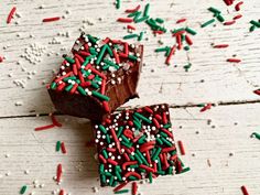 two pieces of chocolate cake with sprinkles on top and white wood background