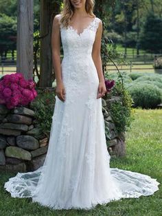 a woman standing in front of a stone wall wearing a wedding dress