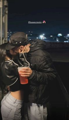 a man and woman kissing in front of a cityscape with the lights on