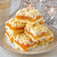 three pieces of apricot coconut crumble bars on a plate next to a cup of coffee