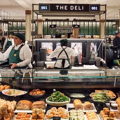 the deli counter is filled with many different types of food and people are ordering