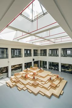 a large room with lots of wooden pieces on the floor and windows above it,