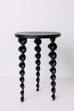 a small black table with spiral legs and a round top on it's side