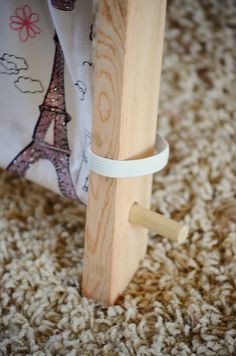 a small wooden object is tied to the floor with white tape and sits on carpet