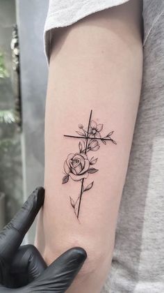 a person with a cross and roses tattoo on their arm