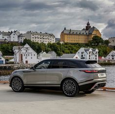 a grey range rover parked in front of a lake with houses on the other side