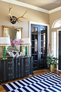 a living room with black and white striped rug, antelope head on the wall