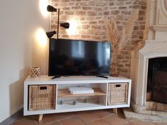 a flat screen tv sitting on top of a white entertainment center next to a fire place