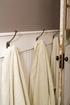 two white towels hanging from hooks on a door