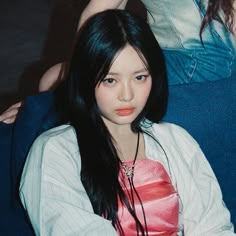 a woman with long black hair sitting on a blue couch