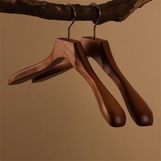 two wooden clothes hangers hanging from a tree branch with hooks on it's sides